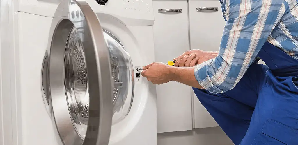 Handyman repairing a clothes dryer and checking electrical connections in Akron, OH
