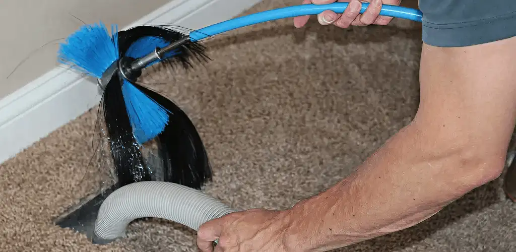 Dryer vent cleaning technician brushing lint from a vent line in Akron, OH