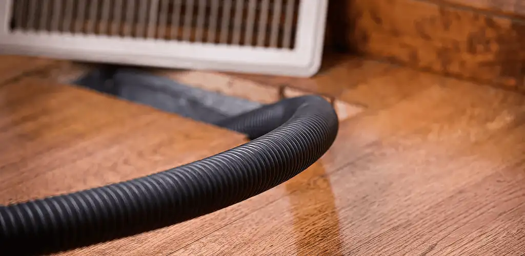 Air duct cleaning hose inserted into a floor vent for ductwork cleaning in Akron, OH