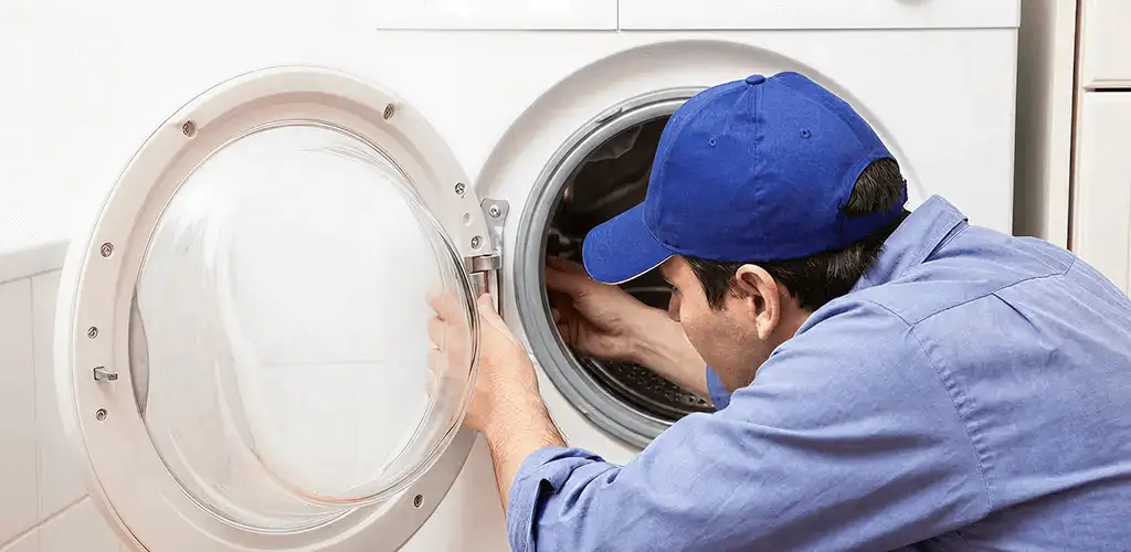 Washing machine repair handyman inspecting a front-load washer drum in Akron, OH