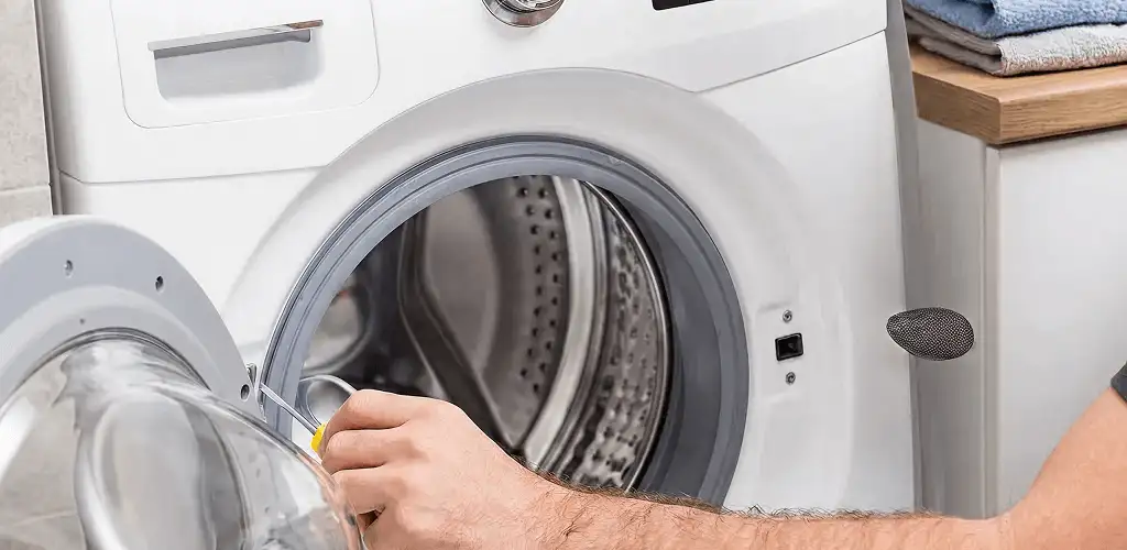 Handyman repairing a front-load washing machine and inspecting the drum in Akron, OH