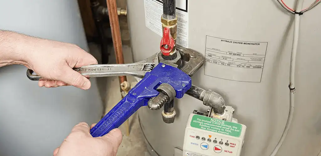 Water heater repair technician tightening the shutoff valve and supply line in Akron, OH